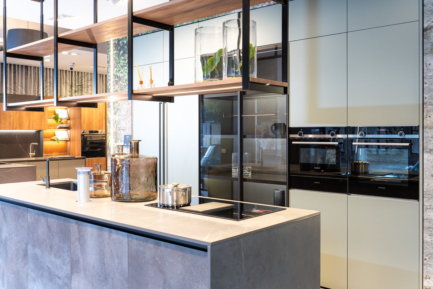 Isola effetto pietra con mensole sospese e colonne forno chiare, nello showroom ARAN Cucine di Gallarate