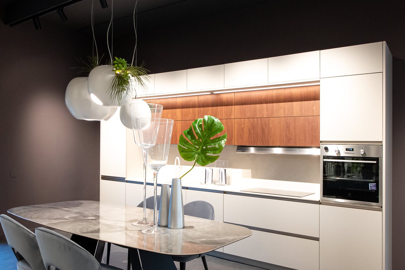 Cucina bianca con inserto in legno e tavolo con piano effetto marmo